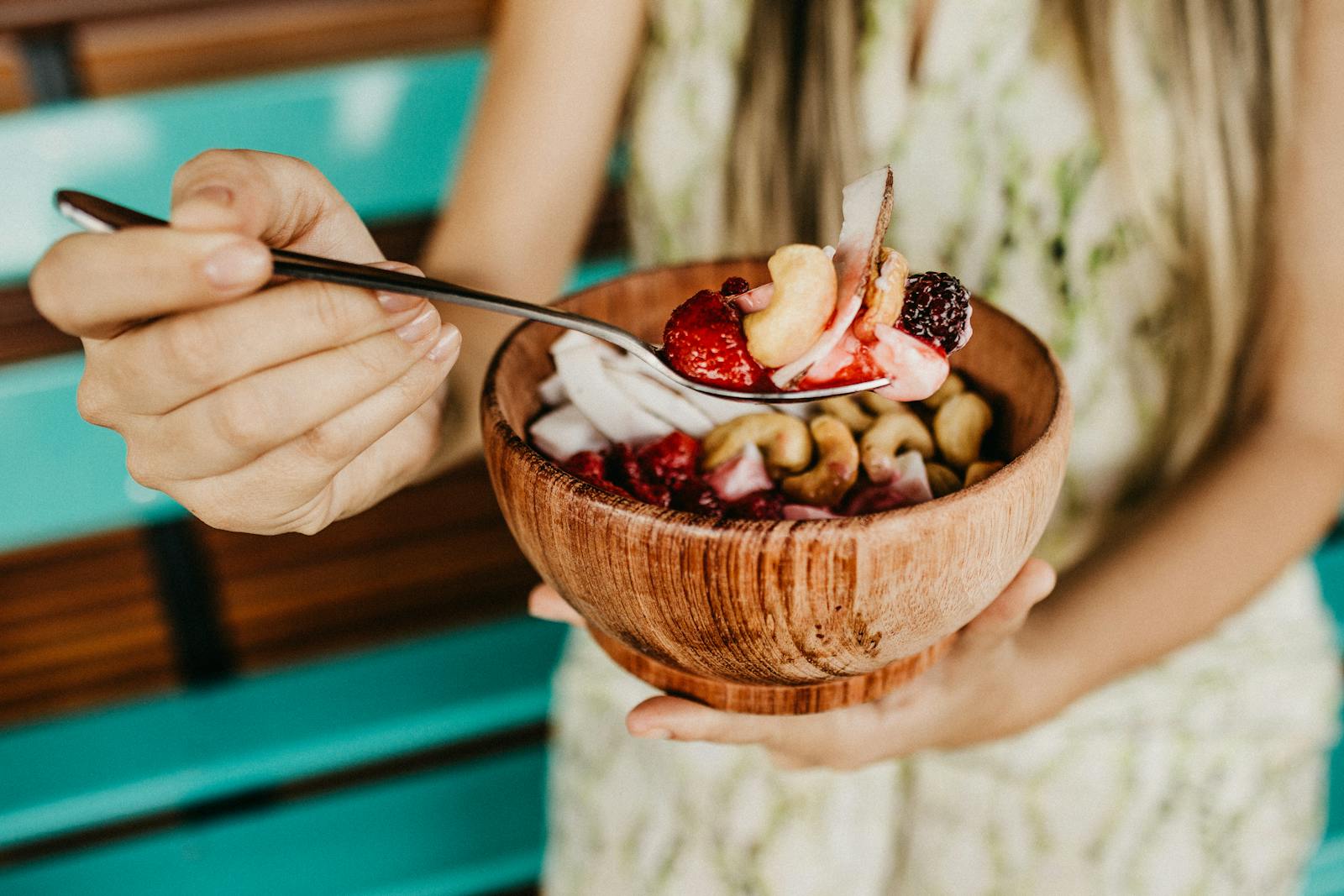 Healthy acai smoothie bowl with fresh berries and nuts held in a wooden bowl.