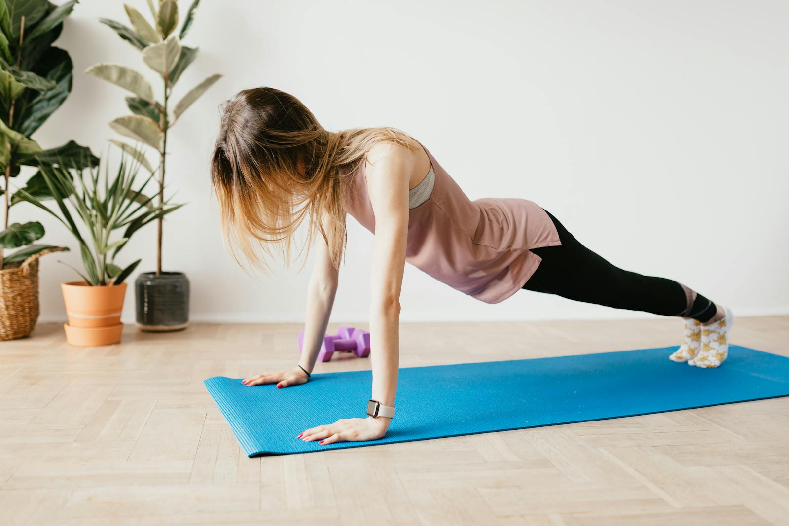 A woman performing plank pose on a mat in a serene home environment with plants.