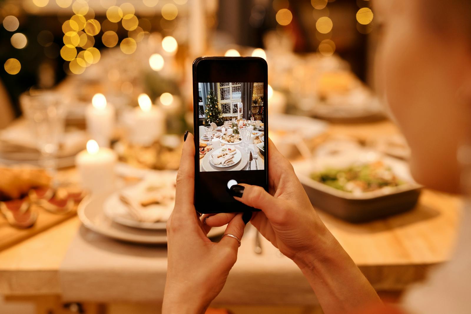 A festive holiday dinner table is photographed using a smartphone, capturing a warm Christmas atmosphere.