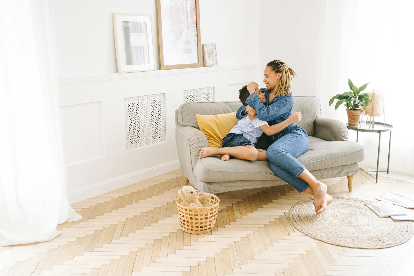 A joyful mother and child embracing on a cozy sofa in a sunlit living room.